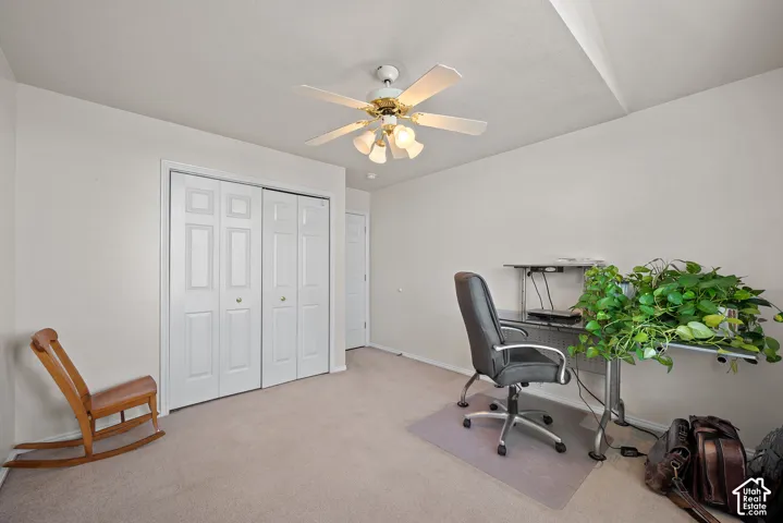 Ceiling fan with integrated lighting, neutral wall paint, white bi-fold closet doors, carpeted flooring, and a white interior door