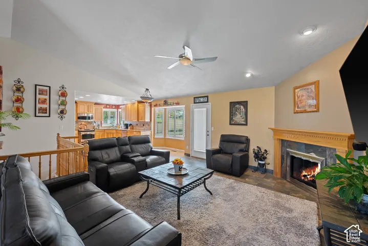 Vaulted ceiling with recessed lighting, corner fireplace with wood mantel, tile hearth, and wood-finish flooring