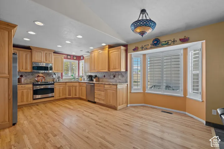 Light wood-finish flooring, natural wood cabinetry, stainless steel appliances, bay window with plantation shutters, and recessed lighting