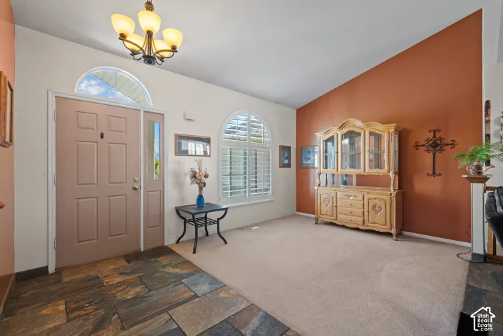 Entryway featuring slate tile flooring, arched transom window, and a five-light chandelier