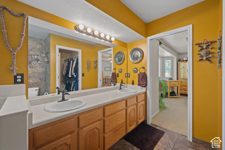 Double vanity with an expansive mirror, light-toned countertop, and wood-finish cabinetry