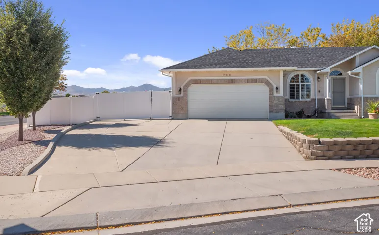 Exterior featuring an attached garage, arched window, front entry steps, and a retaining wall