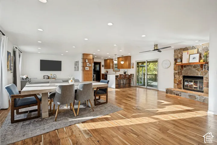 Open-concept interior featuring wood-finish flooring, a stone fireplace, recessed lighting, and a sliding glass door