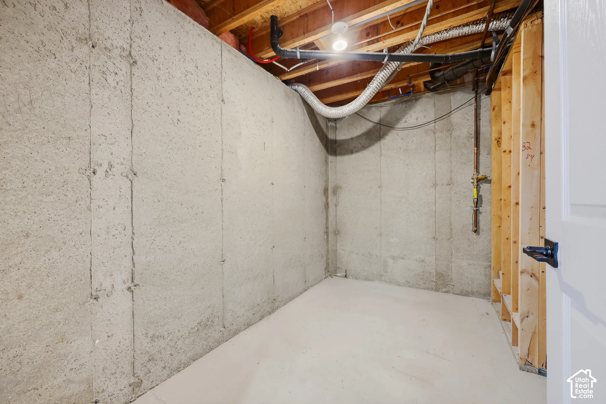 Unfinished lower level featuring concrete walls, exposed ceiling joists, and a concrete floor