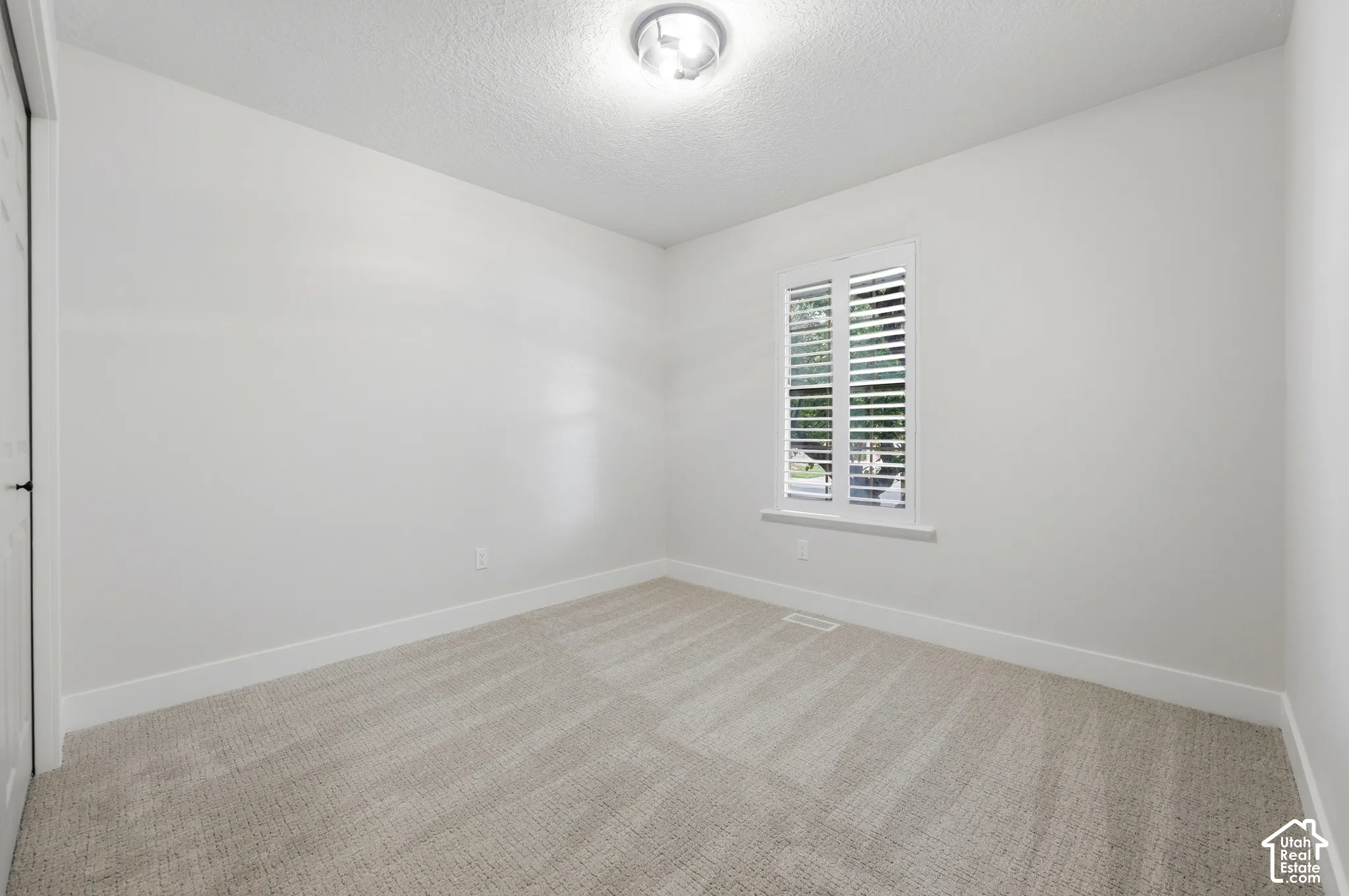 Neutral wall paint, plush carpeting, white window shutters, ceiling-mounted light fixture