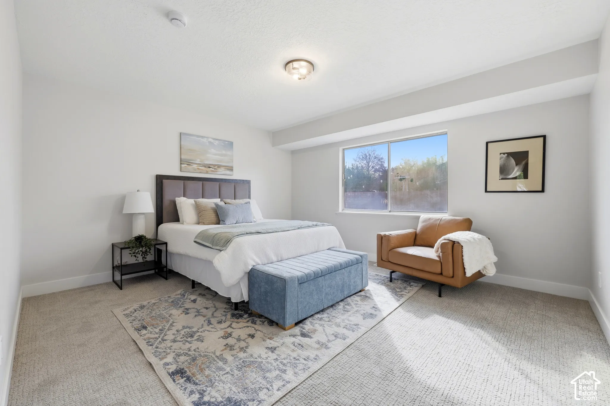 Recessed lighting, large window with outdoor scenery, neutral wall color, and light-toned carpet flooring