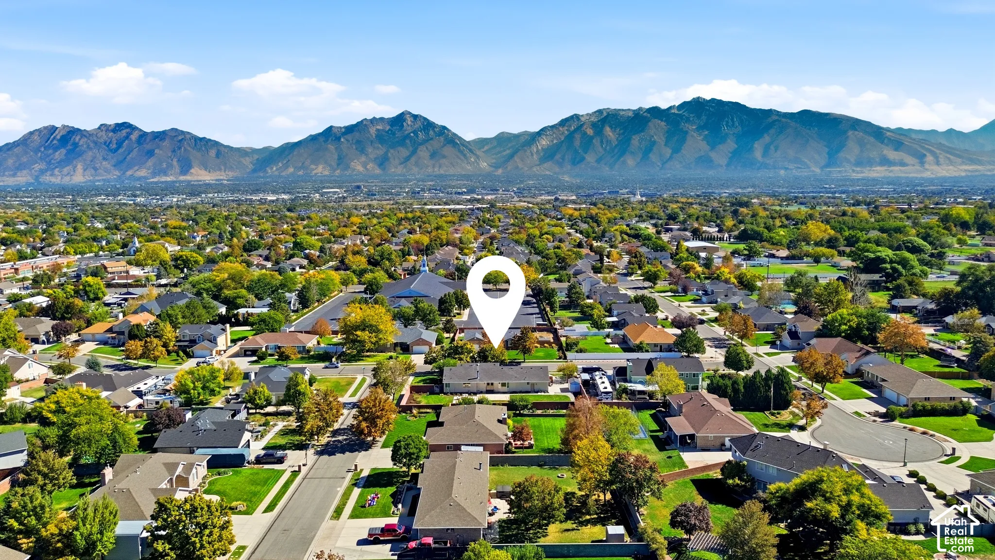 Suburban neighborhood with mature trees, residential streets, and a mountainous backdrop