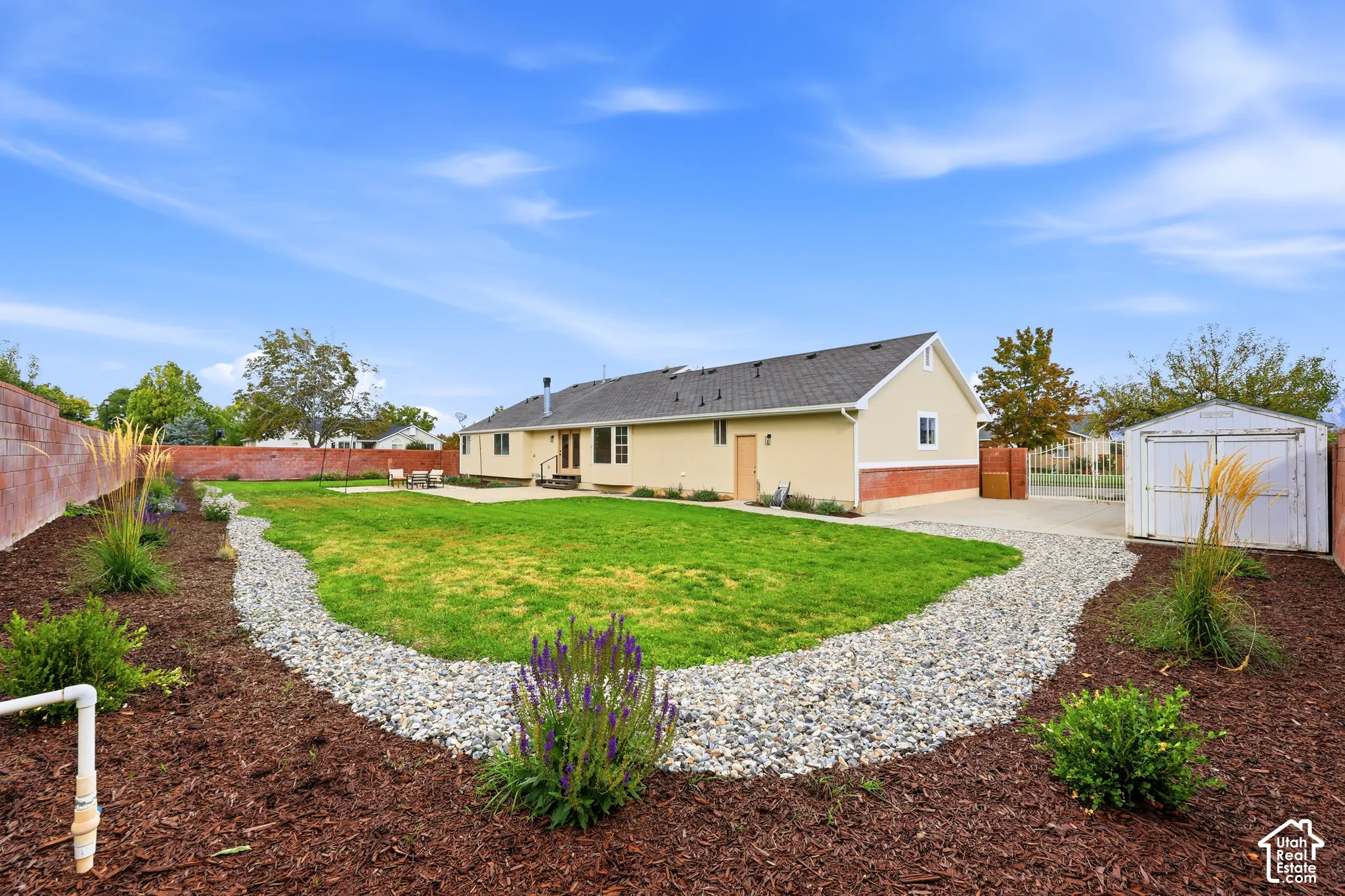 Expansive backyard with a manicured lawn, a large concrete patio, and a gravel pathway