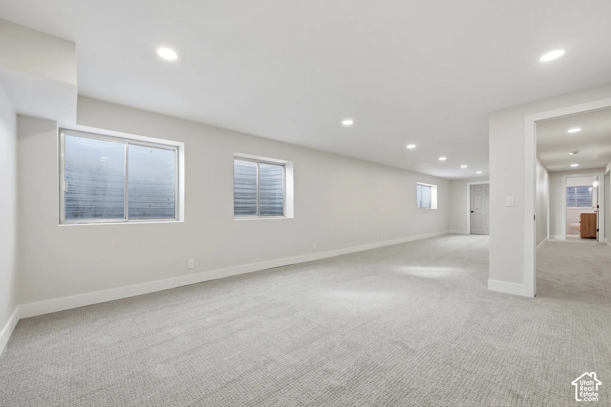 Spacious room with recessed lighting, light gray carpeting, and multiple windows