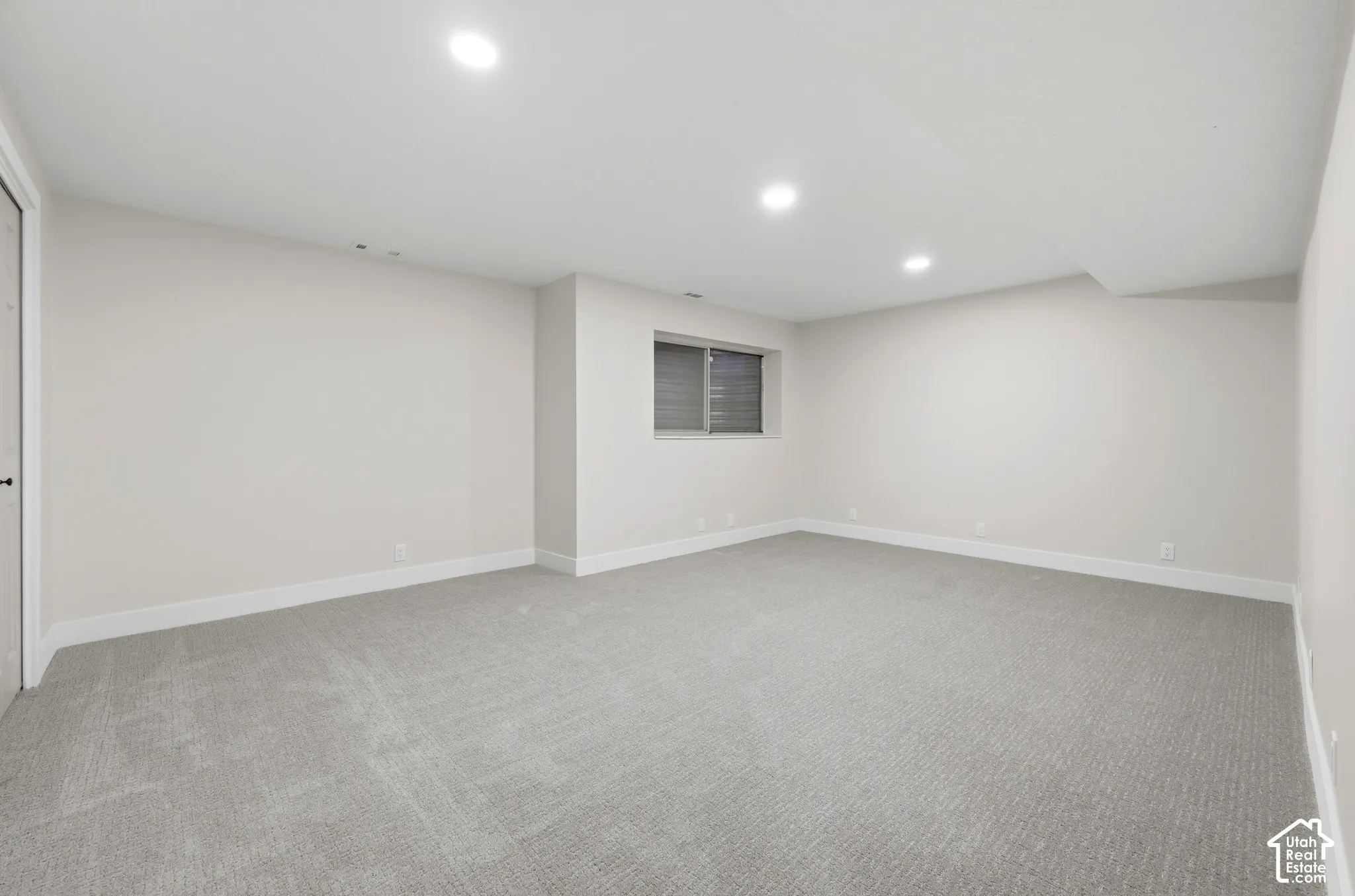 Recessed lighting illuminates the carpeted flooring and light-colored walls
