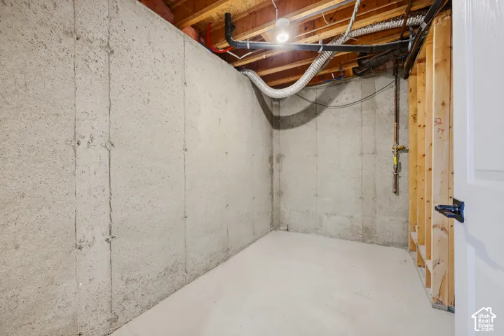 Unfinished lower level featuring concrete walls, exposed ceiling joists, and a concrete floor