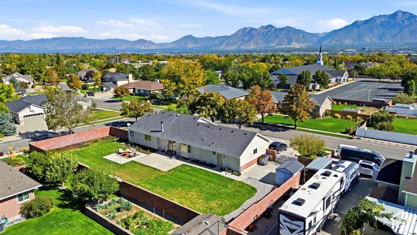 Expansive backyard with a manicured lawn, concrete patio, and garden beds