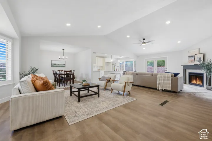 Vaulted ceilings with recessed lighting, wood-finish flooring, and a built-in fireplace with a tiled surround