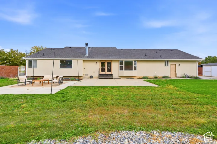 Expansive backyard with a concrete patio, grassy yard, and stucco exterior