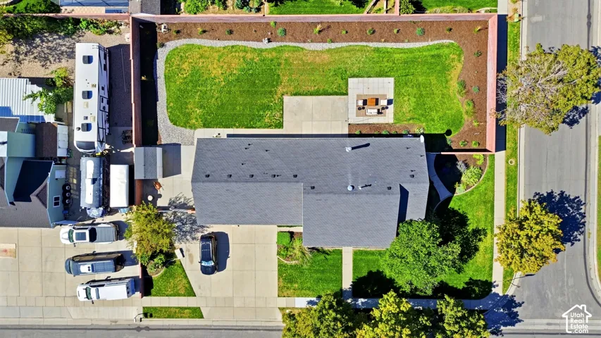 Expansive backyard featuring a manicured lawn, paved patio, and a fire pit