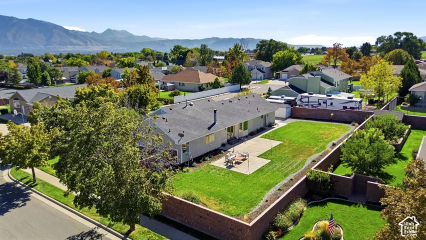 Expansive grassy yard with a concrete patio, surrounded by a brick retaining wall