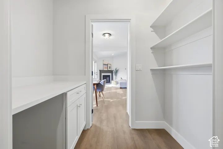White built-in cabinetry with a light-toned countertop, wood-finish flooring, and open shelving