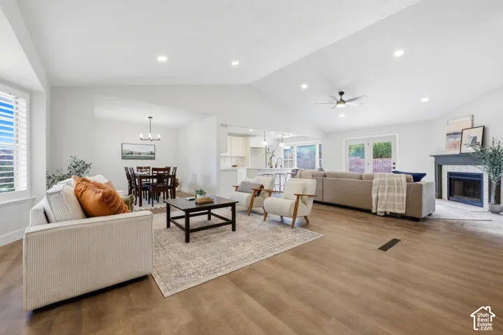 Vaulted ceilings, wood-finish flooring, recessed lighting, and a fireplace with a tile surround