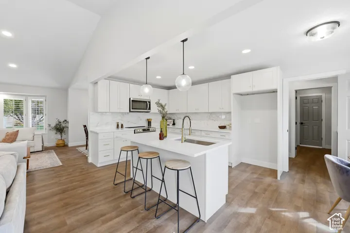Open-concept kitchen with white cabinetry, stainless steel appliances, and a central island with countertop seating