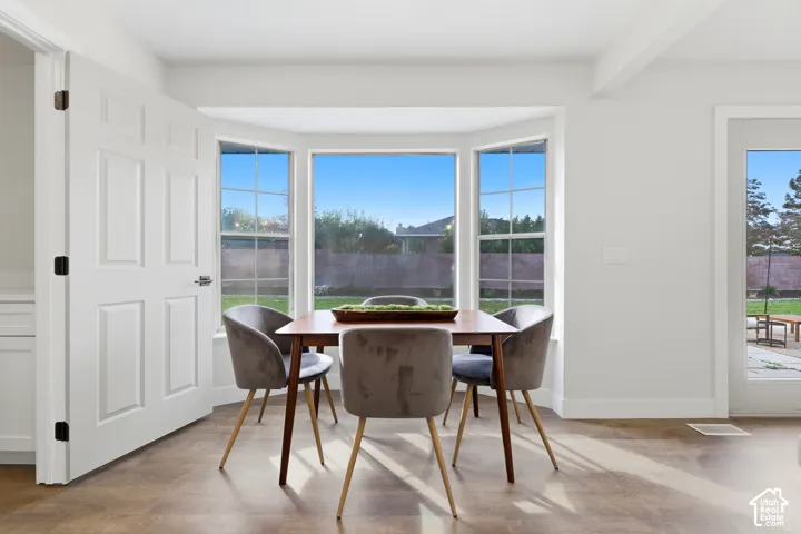 Bay window with multiple panes, wood-finish flooring, white paneled door, and white walls