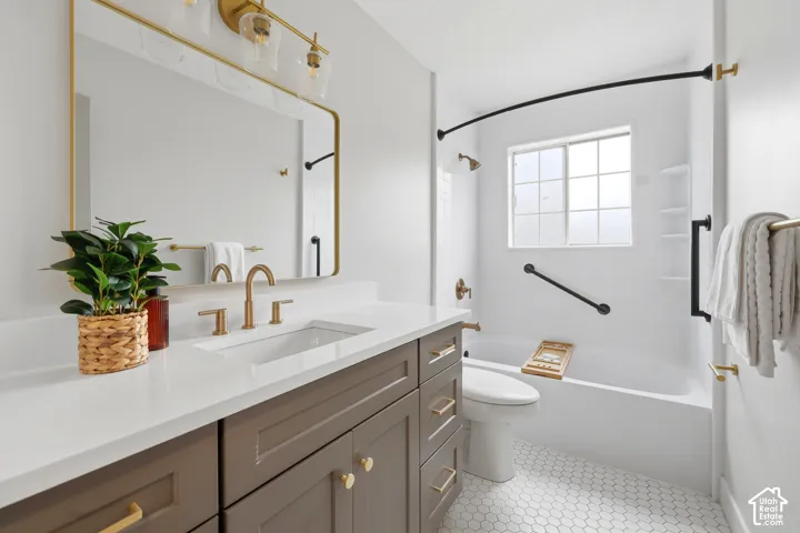 Modern bathroom featuring a single vanity with stone countertop, white hexagonal floor tiles, and a tub-shower combination