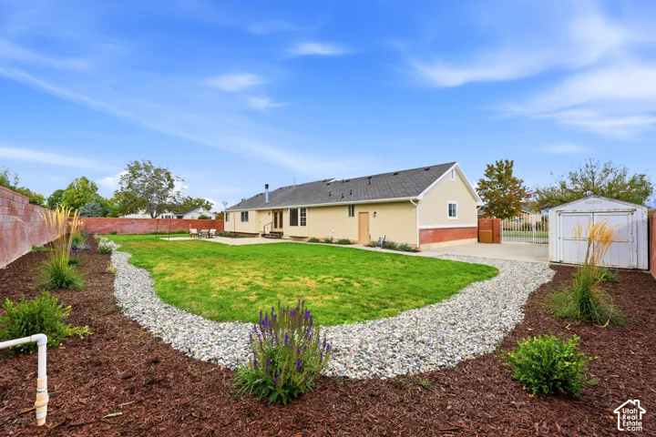 Expansive backyard with a manicured lawn, a large concrete patio, and a gravel pathway