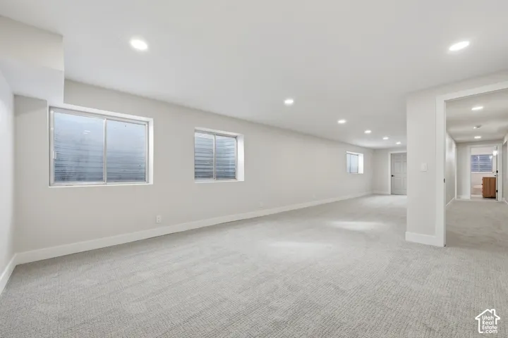 Spacious room with recessed lighting, light gray carpeting, and multiple windows