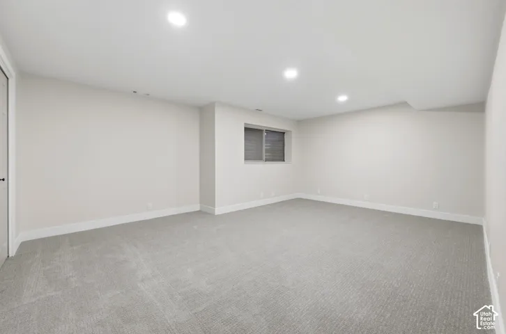Recessed lighting illuminates the carpeted flooring and light-colored walls