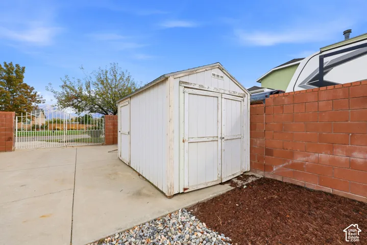 Outdoor storage shed with dual-entry doors, concrete pad, and an adjacent red brick privacy wall