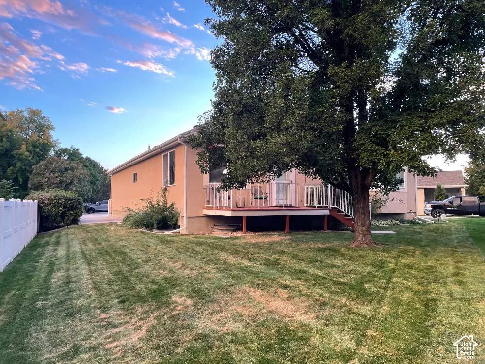 Back of home with deck, lawn, mature tree, and fence along Jordan Canal
