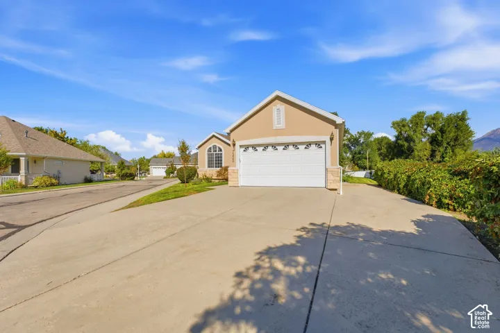 Stucco exterior with a peaked roof, arched window detailing, two-car garage, and extra parking for up to five vehicles