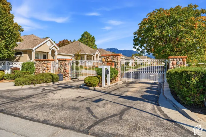 Entry gate to small, private community with wrought iron fencing and beautiful landscaping