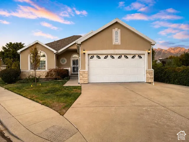 Stucco exterior featuring stone accents, an arched window, and a double-car garage with decorative window inserts