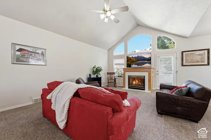 Vaulted ceiling with a ceiling fan, arched windows, and gas fireplace