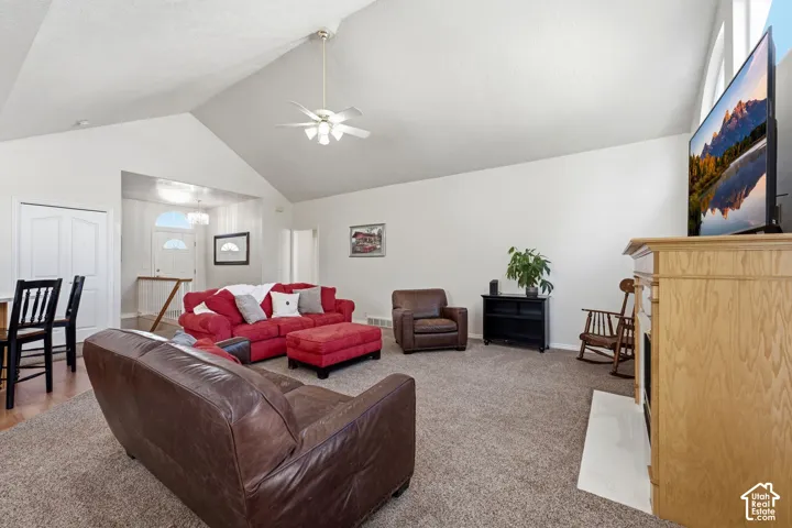 Vaulted ceiling with a ceiling fan, carpeted flooring