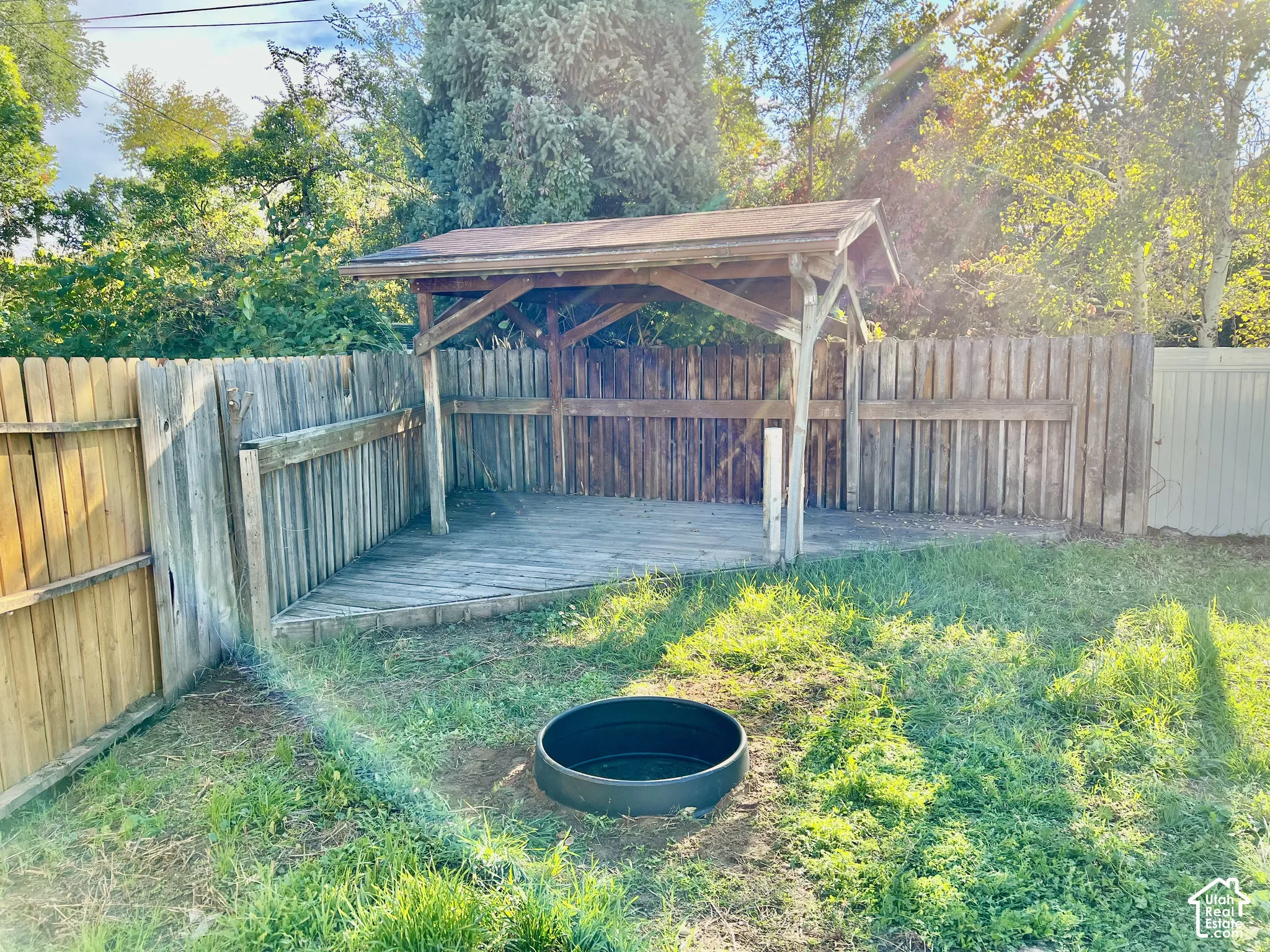 Fenced yard featuring a covered wooden deck structure and a recessed fire pit