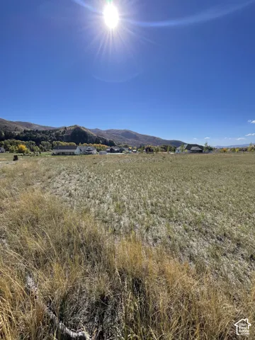 Expansive undeveloped land with distant mountain ranges and residential structures