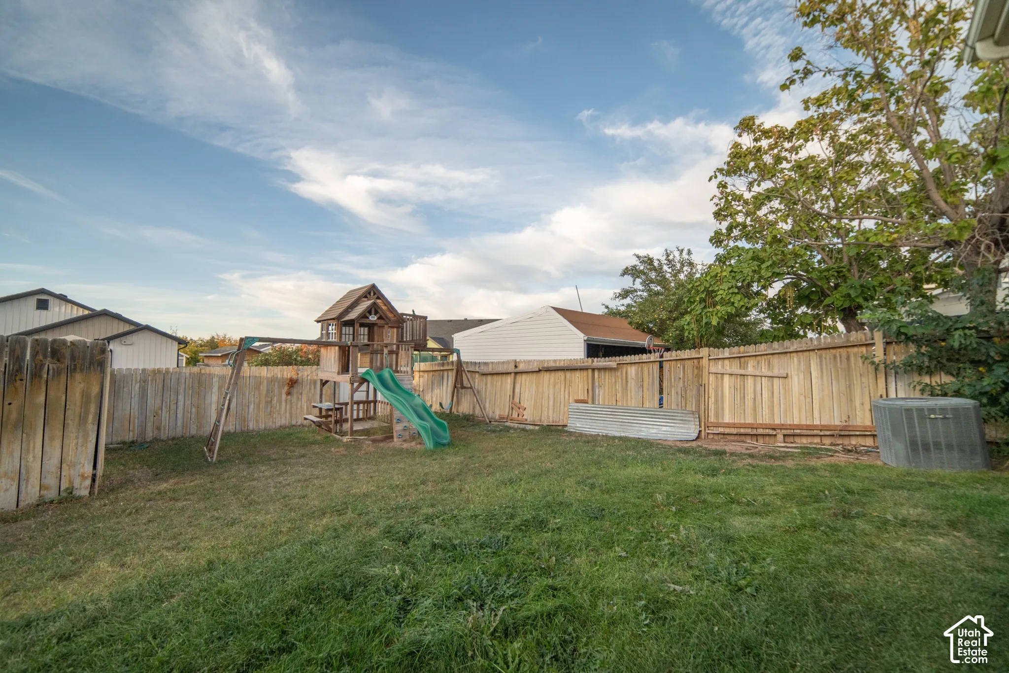 Expansive backyard featuring a natural grass lawn and wood privacy fencing
