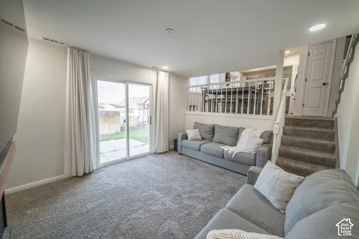 Sliding glass door to the exterior, carpeted flooring, recessed lighting, and a white wood railing