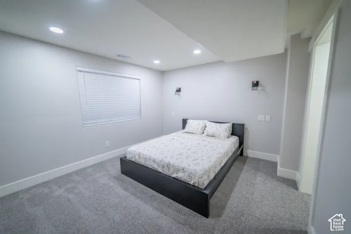 Recessed lighting, wall-mounted sconces, and a window with blinds provide ambient illumination