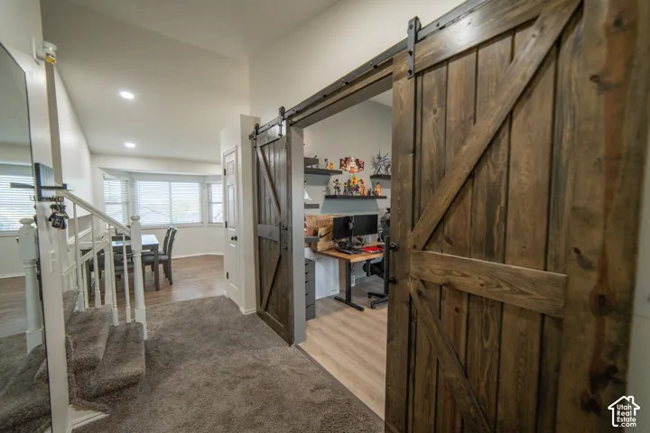 Rustic wood-finish barn door, recessed lighting, wood-finish flooring, bay window, carpeted staircase