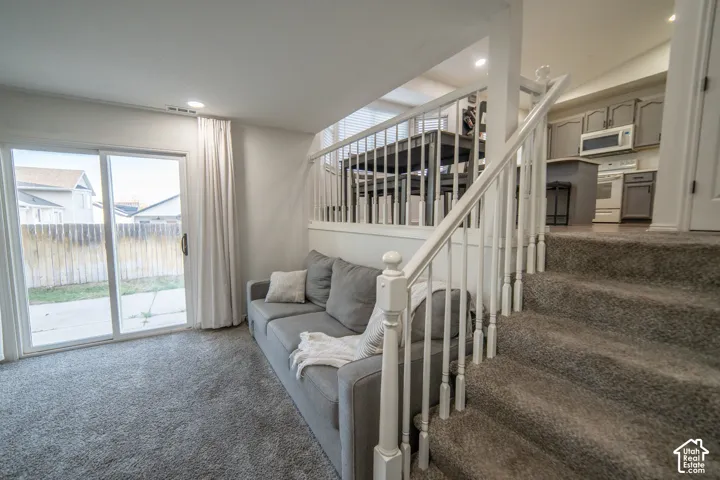 Sliding glass door leading to the outdoor space, overhead recessed lighting, and carpeted flooring