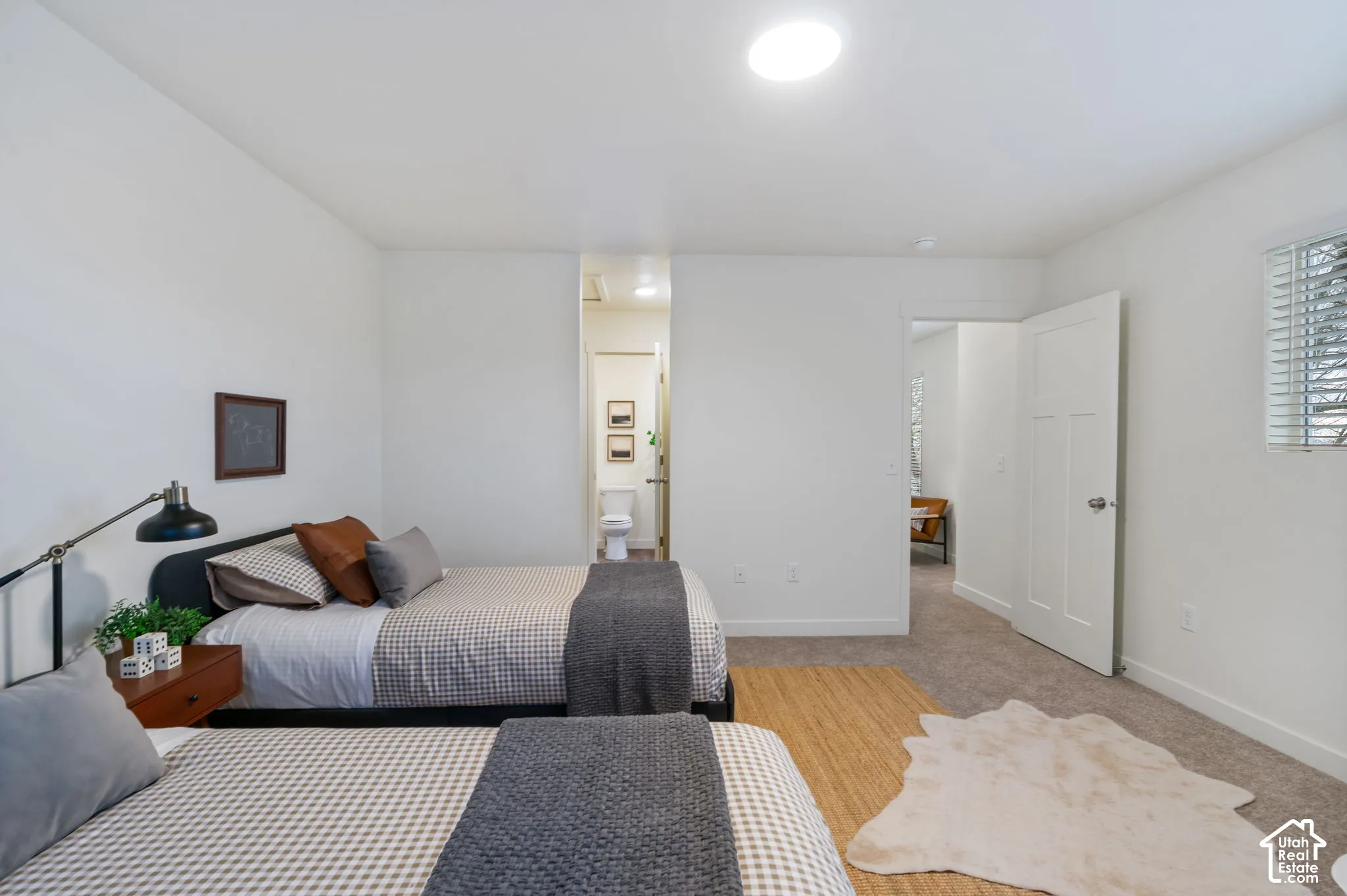 Neutral white walls with recessed ceiling lighting, a privacy window with blinds, and light-toned carpet flooring