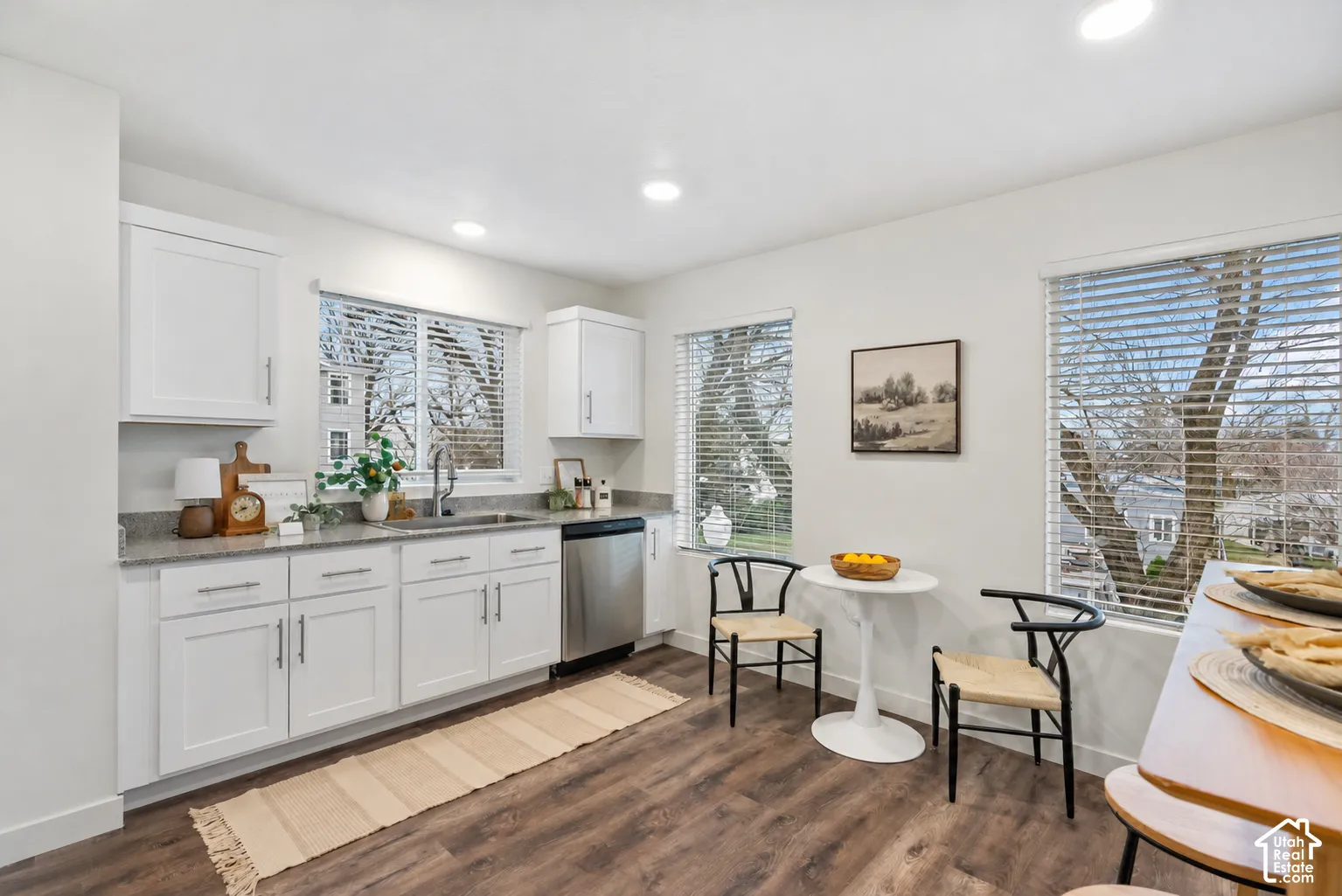 Kitchen featuring white cabinetry, stainless steel appliances, granite-style countertops, and wood-finish flooring