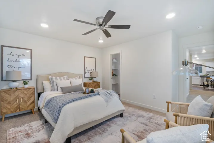 Recessed lighting, ceiling fan, built-in shelving, upholstered headboard, and wood-finish cabinetry