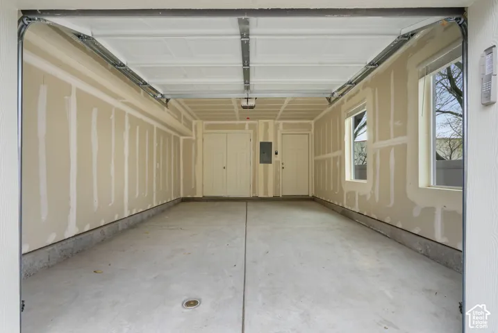 Two-car garage with concrete flooring, two windows, and two interior doors