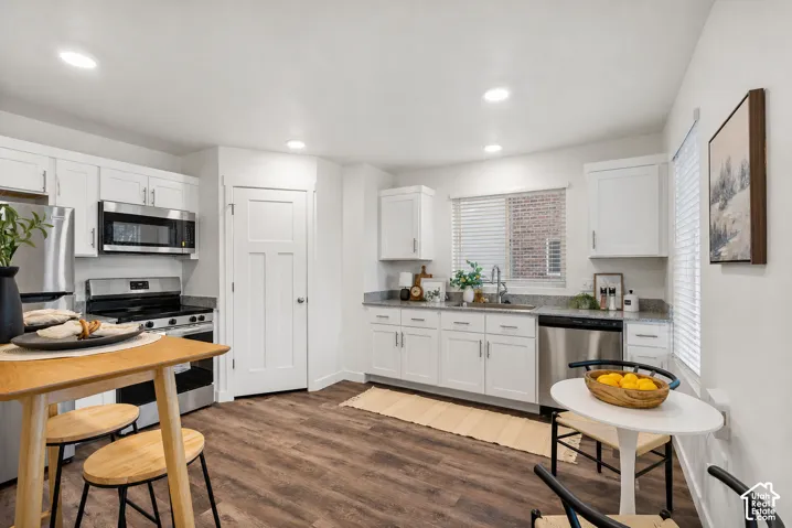Kitchen featuring stainless steel appliances, white cabinetry, wood-finish flooring, and recessed lighting