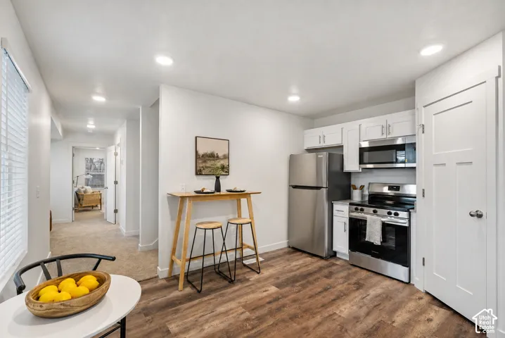 Kitchen featuring stainless steel appliances, white cabinetry, and wood-finish flooring