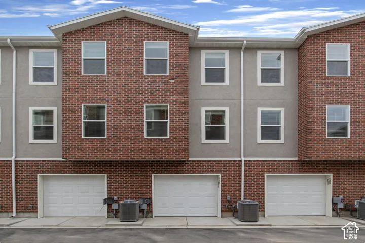 Brick and stucco exterior with multiple windows and attached garage access