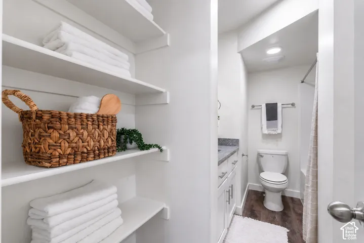 Built-in shelving, wood-finish flooring, white vanity with stone countertop, and recessed lighting